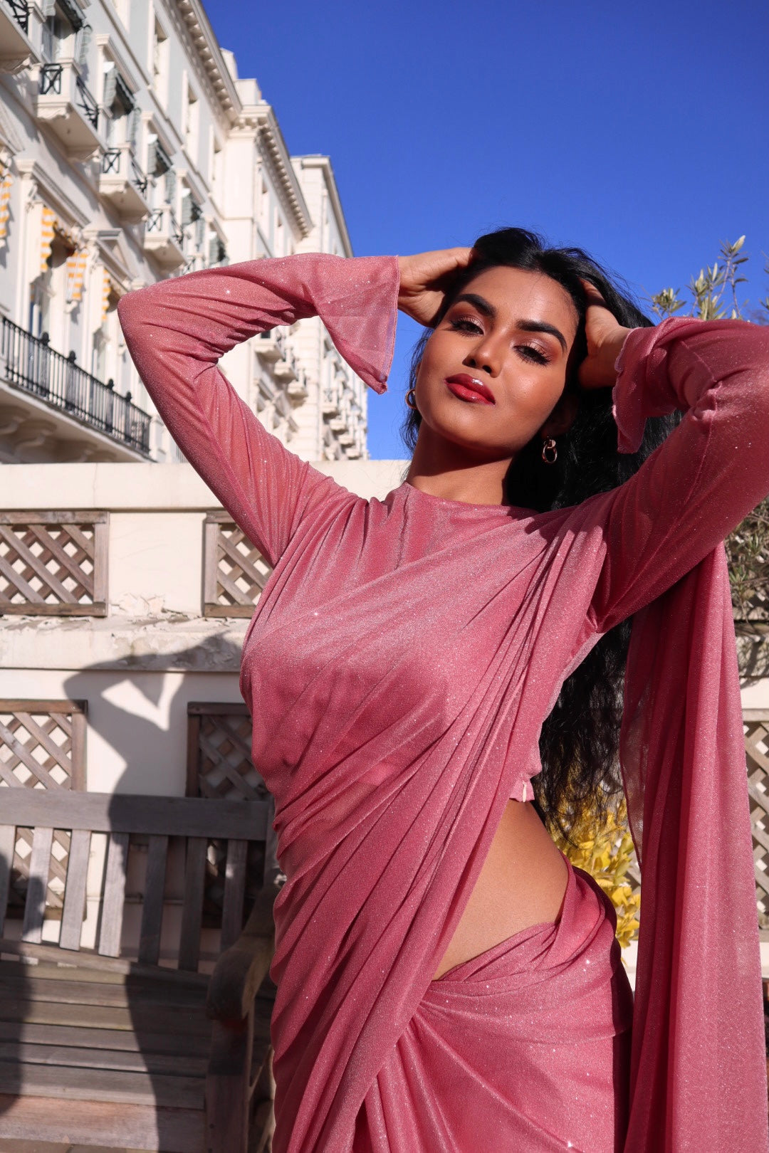 "An elegant dark pink long sleeve saree with a touch of sparkle, perfect for special occasions. The saree features a glittery fabric that adds a glamorous touch to the overall look."