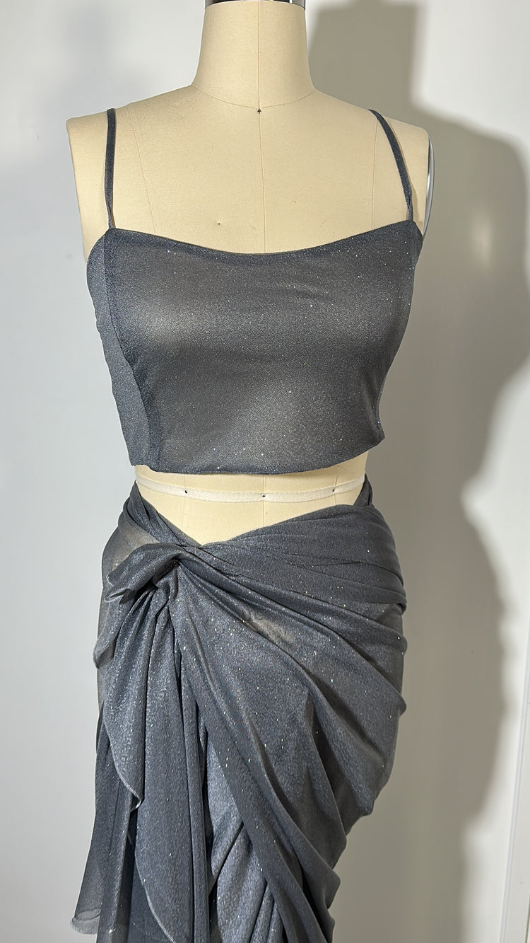 "A stunning silver glitter saree with spaghetti straps, combining elegance and sparkle in one captivating ensemble. The shimmering fabric and delicate spaghetti straps create a mesmerizing and glamorous look, perfect for any glamorous occasion."