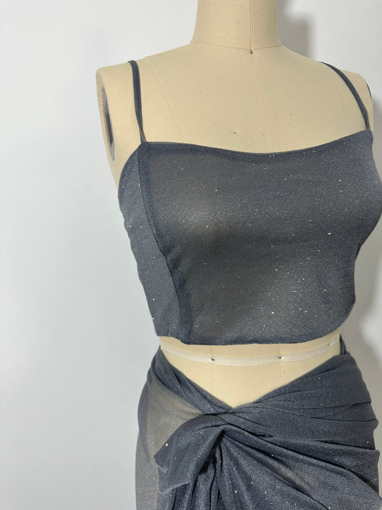 "A stunning silver glitter saree with spaghetti straps, combining elegance and sparkle in one captivating ensemble. The shimmering fabric and delicate spaghetti straps create a mesmerizing and glamorous look, perfect for any glamorous occasion."