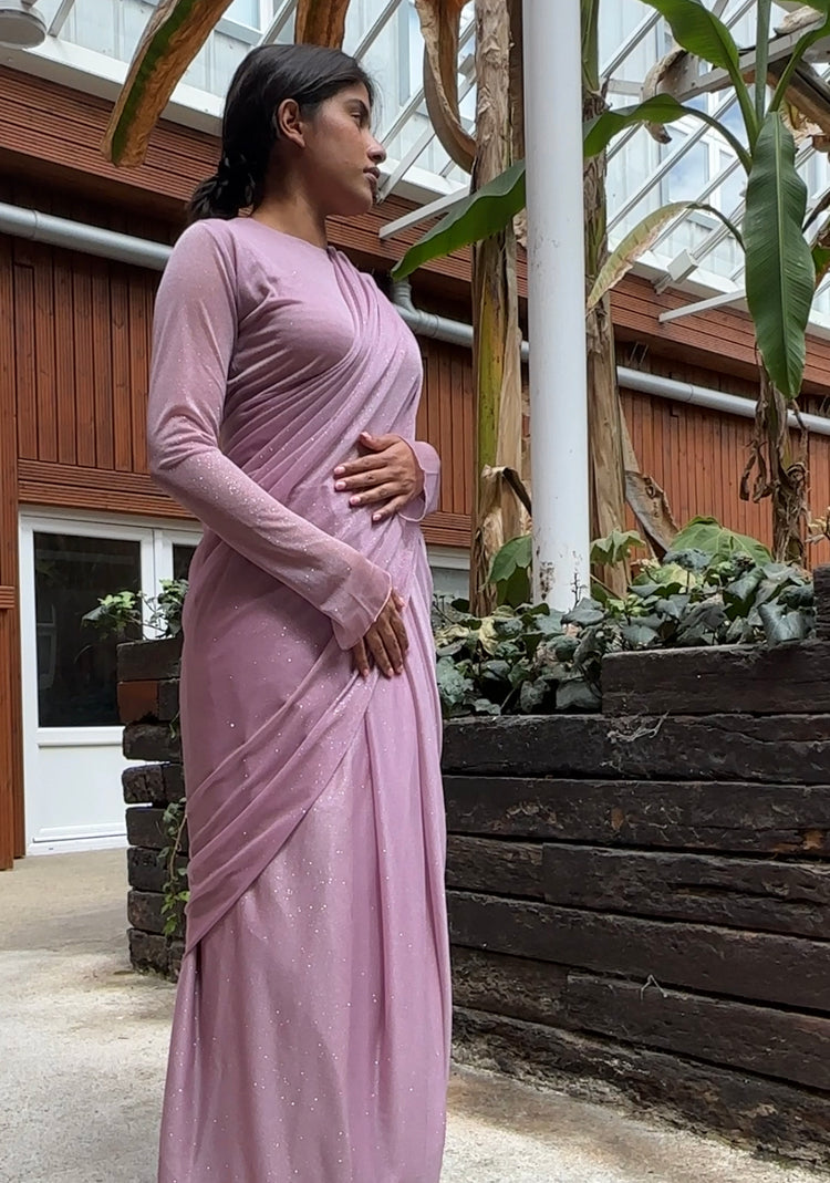 "A beautiful lilac long sleeve saree adorned with glitter, creating a mesmerizing and enchanting look. The shimmering fabric adds a touch of glamour and elegance, making it an ideal choice for any special event or celebration."