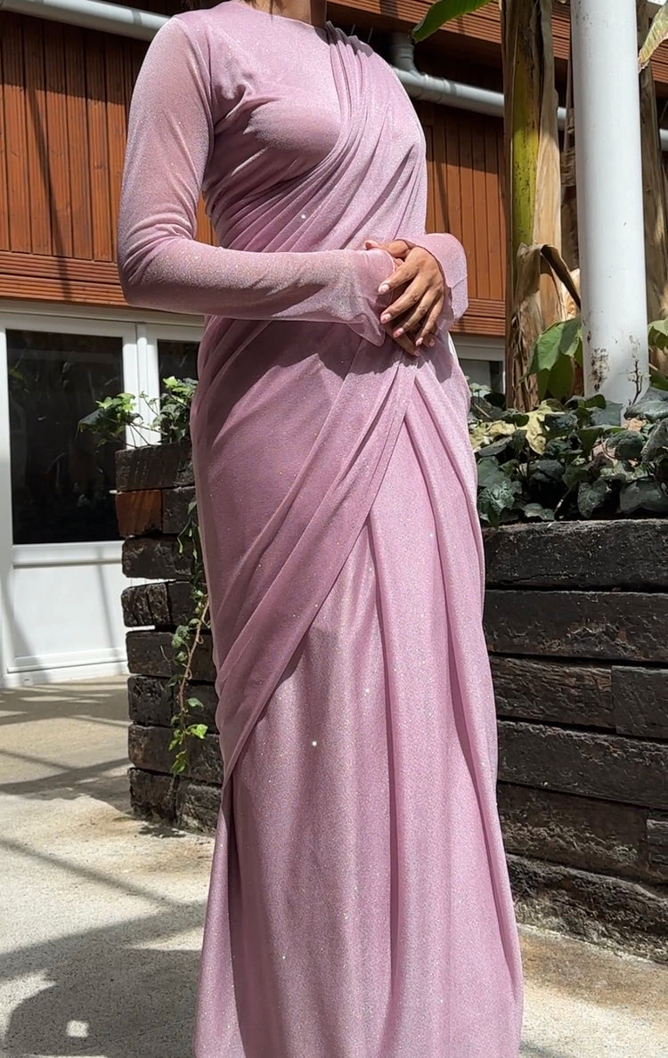 "A beautiful lilac long sleeve saree adorned with glitter, creating a mesmerizing and enchanting look. The shimmering fabric adds a touch of glamour and elegance, making it an ideal choice for any special event or celebration."
