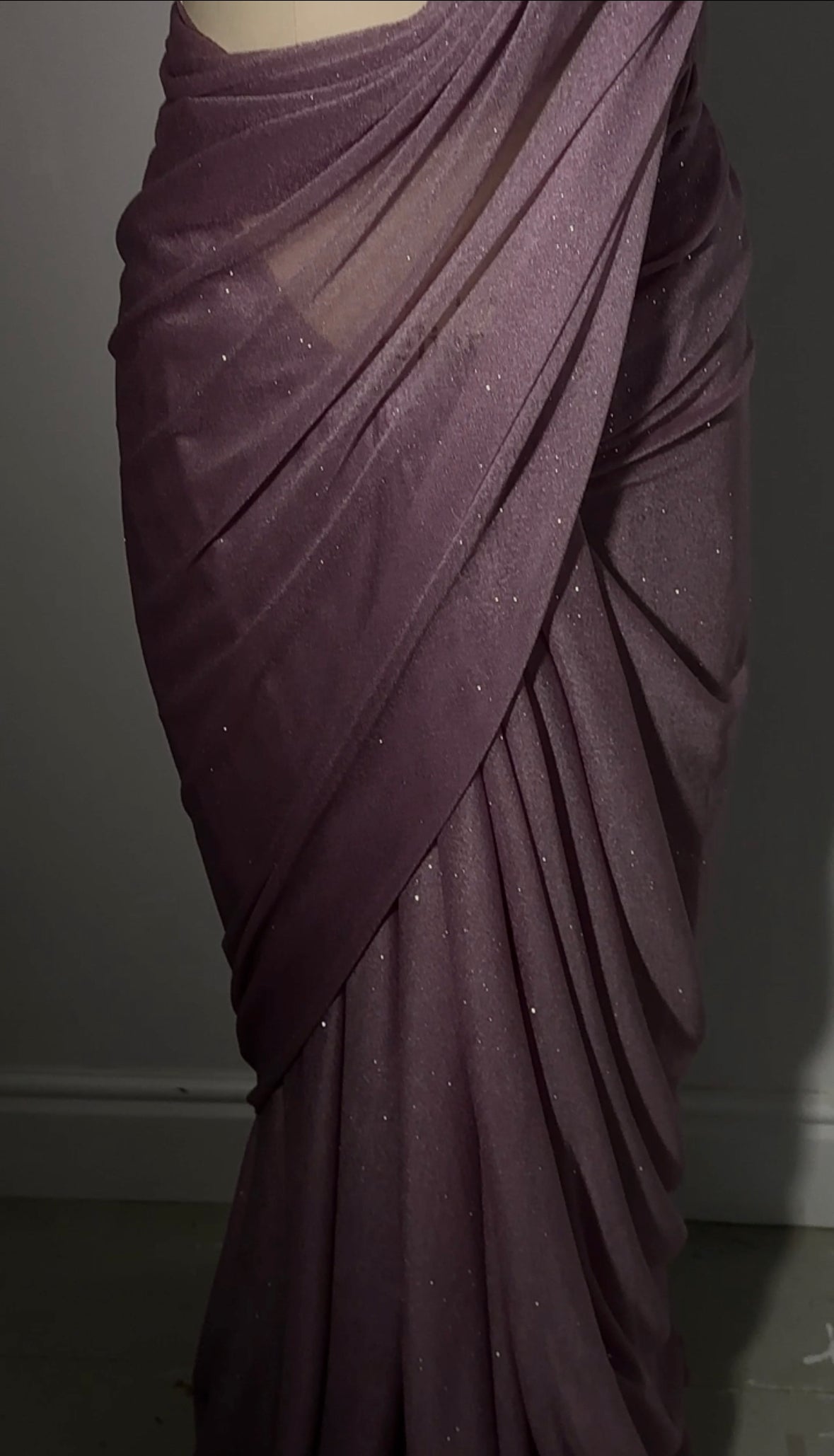"A beautiful lilac long sleeve saree adorned with glitter, creating a mesmerizing and enchanting look. The shimmering fabric adds a touch of glamour and elegance, making it an ideal choice for any special event or celebration."