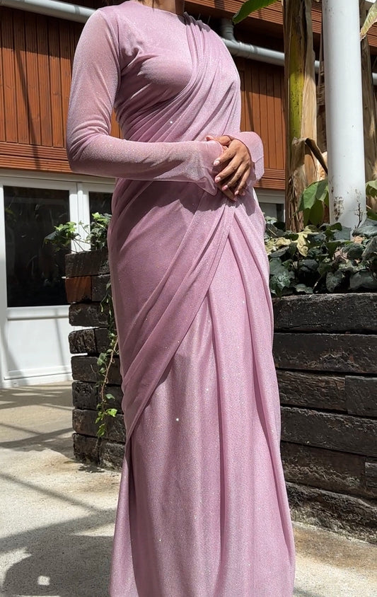 "A beautiful lilac long sleeve saree adorned with glitter, creating a mesmerizing and enchanting look. The shimmering fabric adds a touch of glamour and elegance, making it an ideal choice for any special event or celebration."